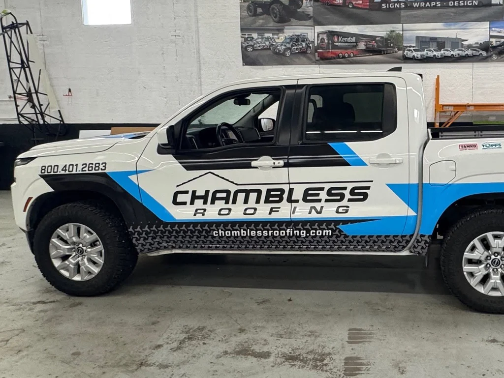Graphic design and vehicle graphics for Chambless Roofing featuring bold blue, black, and white company branding, phone number, and website on a pickup truck.