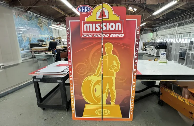 NHRA Mission Drag Racing Series promotional display featuring bold branded graphics and a trophy illustration.
