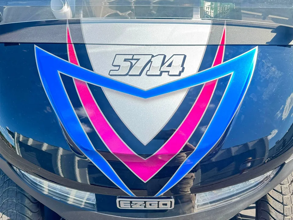 Vehicle wrap design featuring bold blue, pink, silver, and black graphics with the number 5714 applied across the front of an E-Z-GO cart.