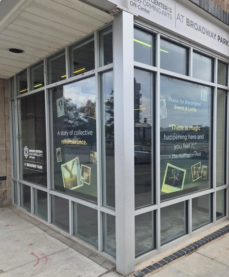 Custom window decals promoting a Sweet & Lucky exhibit, featuring branded text, quotes, and photo graphics across large storefront windows.