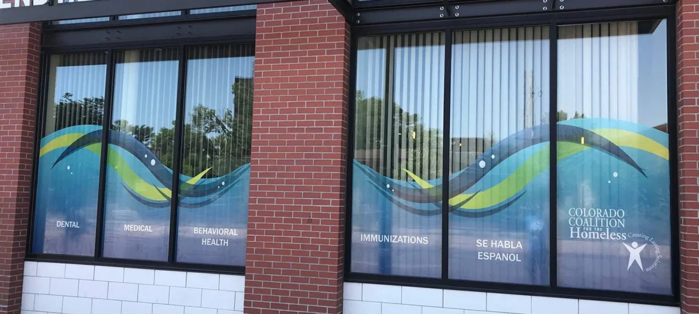 Window graphics for Colorado Coalition for the Homeless featuring colorful branded wave designs.